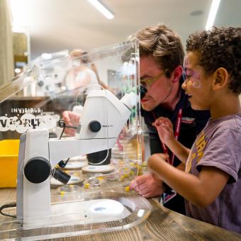 Adult helping child look at microscope